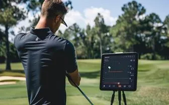 Golfer checking a launch monitor screen on the course