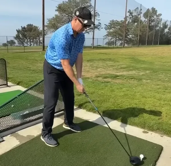 Golfer wearing CaddieVision glasses addressing the ball at a driving range